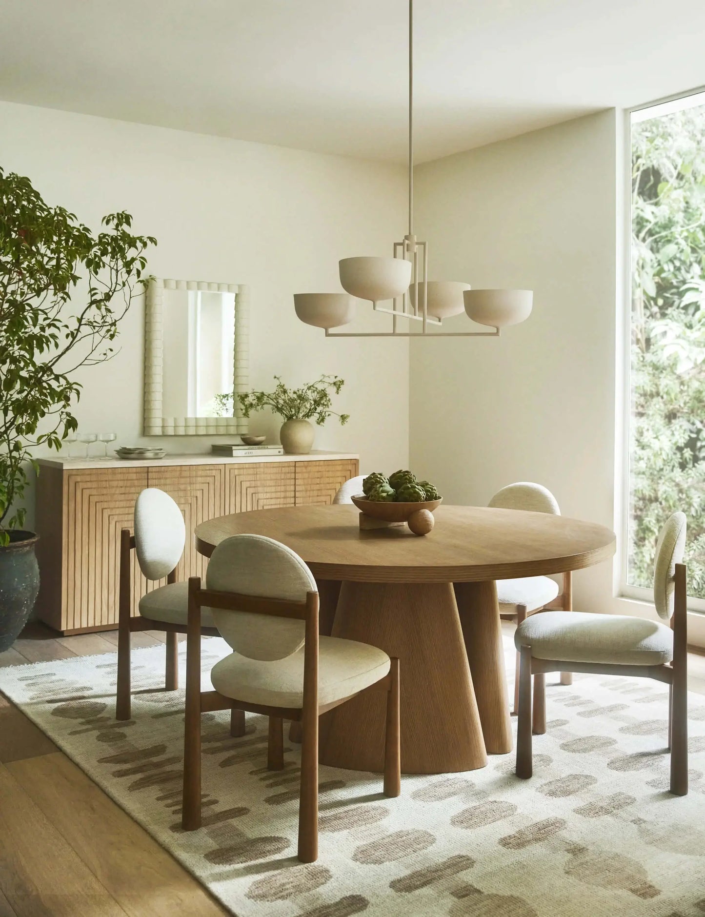 Badr Dining Chair set in a minimalist dining room with a round wooden table and contemporary lighting.