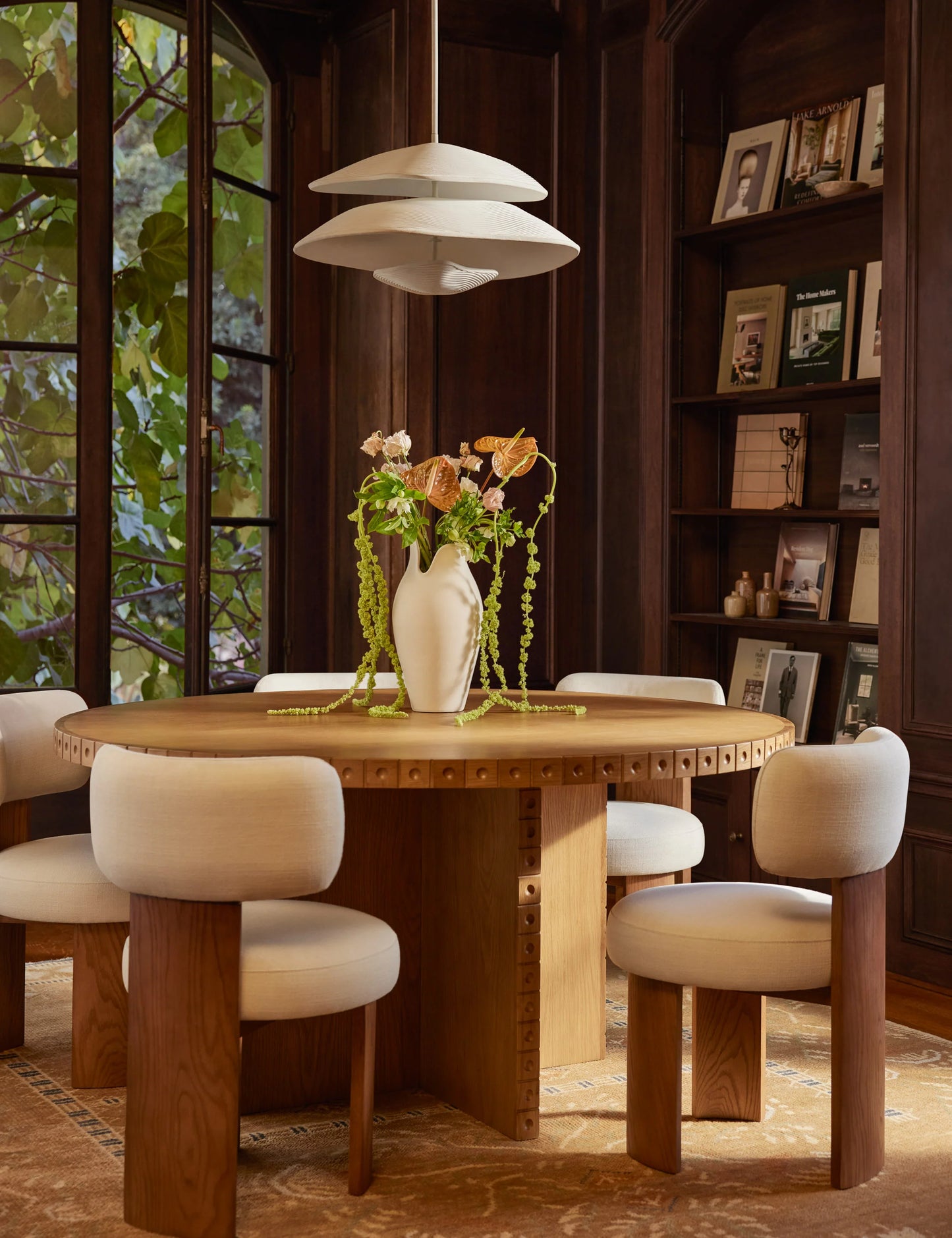 نور Nour Round Oak Dining Table styled in a luxury dining room, showcasing its warm wood tones and elegant detailing.