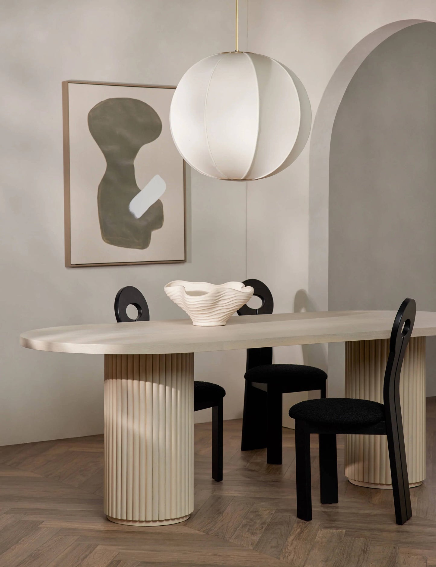 Modern minimalist dining room with the Meis Oval Dining Table, showcasing its warm acacia wood finish and sculptural base.