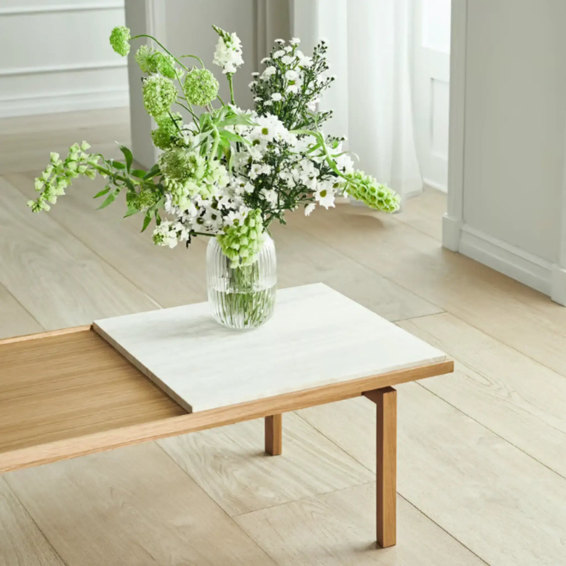 Raha Table styled with white marble insert and fresh flowers in a light-filled room
